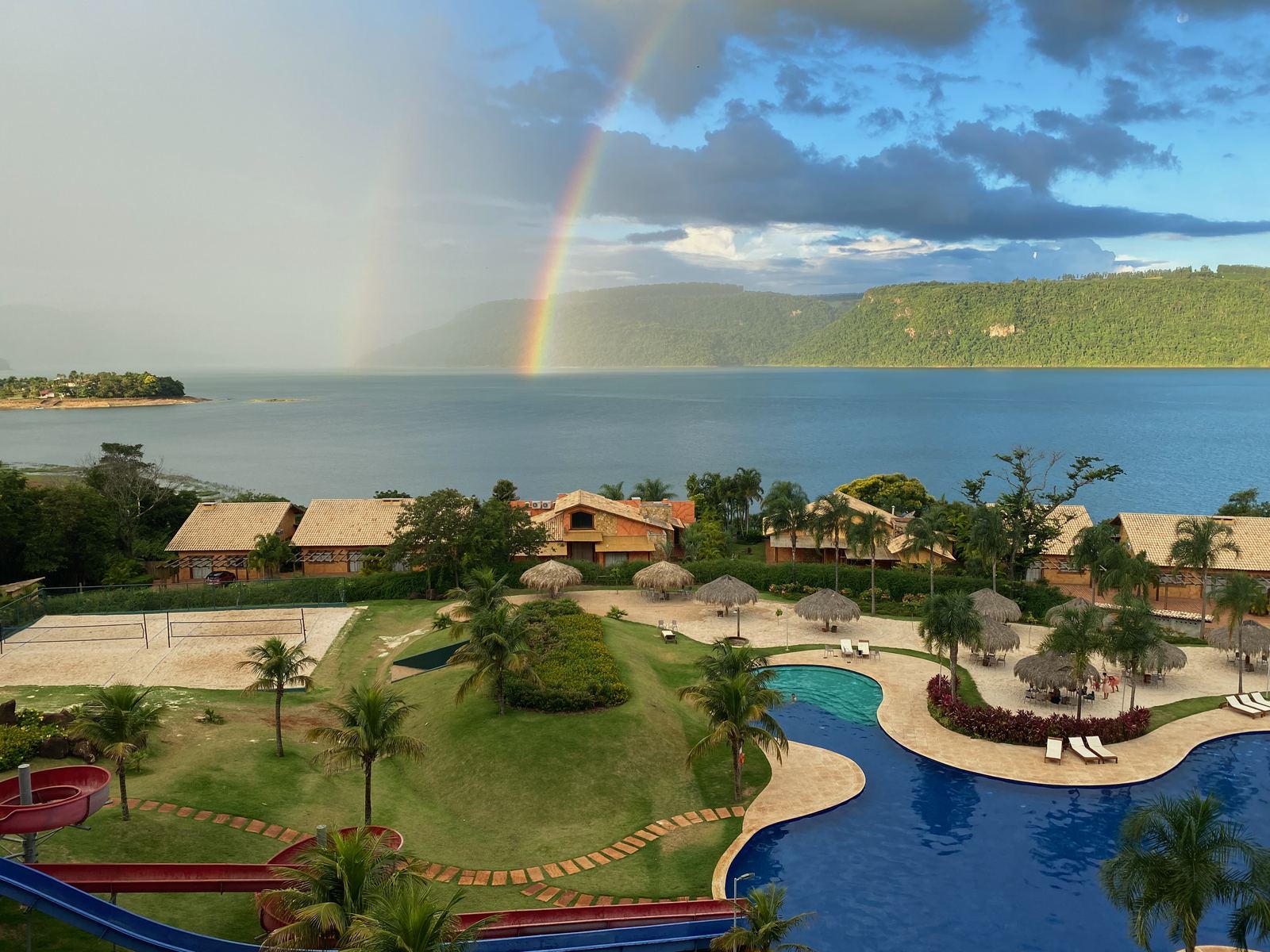 The Tayayá resort beside a reservoir with a rainbow in the sky.