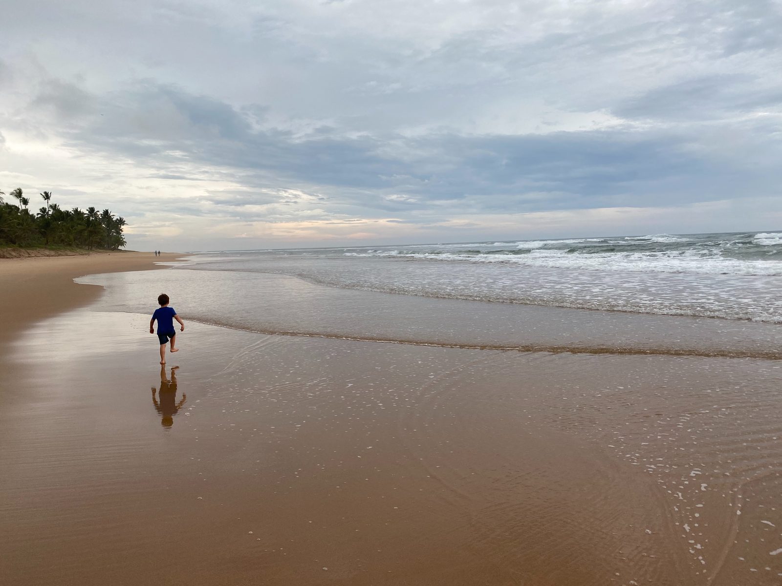 A child running along the sand on the beach at Barra Grande, facing the sea.